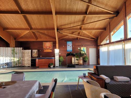 - une piscine dans une pièce avec une table et des chaises dans l'établissement La Belle Demeure, à Aumagne
