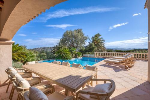 un patio avec une table et des chaises et une piscine dans l'établissement Sainte-Maxime - Villa de standing avec piscine & vue mer, à Sainte-Maxime