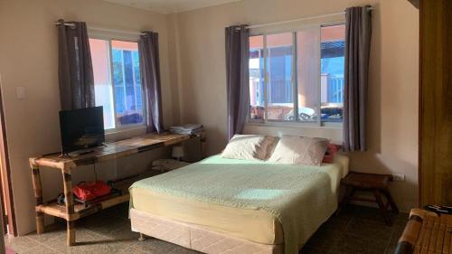 a bedroom with a bed with a desk and two windows at Marinas private beach resort in Tangalan