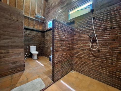 a brick bathroom with a shower and a toilet at Batu Jaran Hill Cottage Uluwatu in Uluwatu