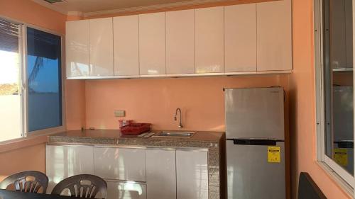 a kitchen with white cabinets and a stainless steel refrigerator at Marinas private beach resort in Tangalan