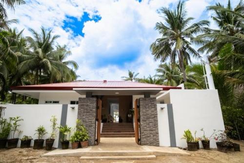a small white house with palm trees in the background at Vida Homes Sipalay in Sipalay