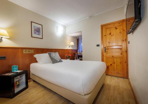 a bedroom with a large white bed and a door at iH Hotels Courmayeur Mont Blanc in Courmayeur
