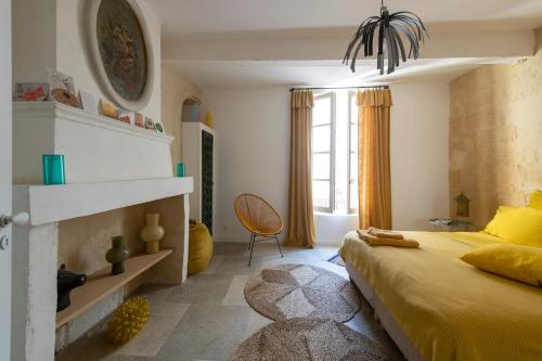 - une chambre avec un lit jaune et une cheminée dans l'établissement Chez Domus Reattu Arles centre, à Arles