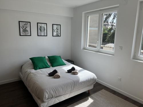 a white bedroom with a bed with green pillows at Résidence Claire Roman in Valence