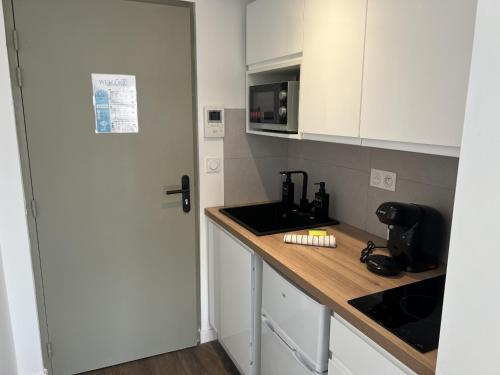 a kitchen with a counter and a sink and a microwave at Résidence Claire Roman in Valence
