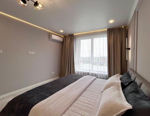 Un dormitorio con una cama grande y una ventana. en Новая Раимбек Резиденс 13-65 & питьевая вода в подарок, en Almaty