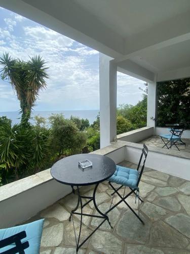a table and chair on a balcony with a view of the ocean at Amazing seaside beach home in the best location in Agios Ioannis Pelio