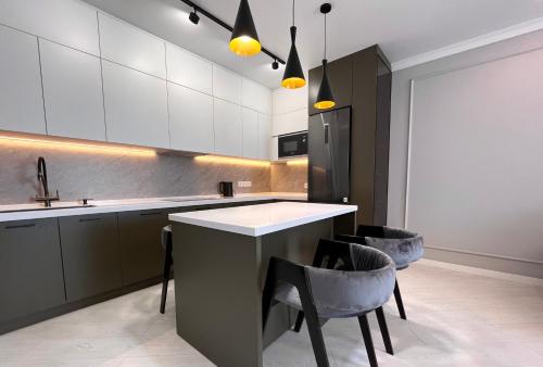 una cocina con encimera y algunas sillas. en Новая Раимбек Резиденс 13-65 & питьевая вода в подарок, en Almaty