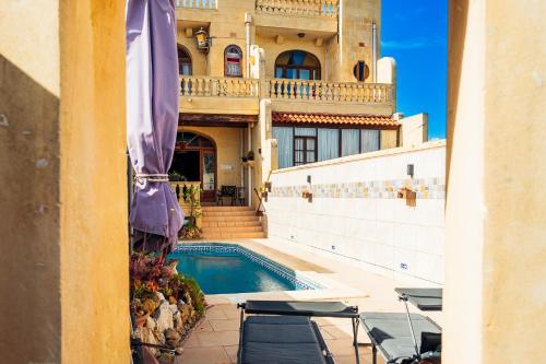 a house with a swimming pool in front of a building at Narcisa Farmhouse B&B in Nadur