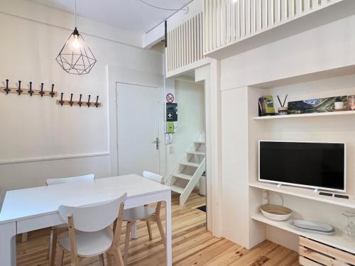 une cuisine et une salle à manger avec une table et des chaises blanches dans l'établissement Studio plein centre, à Cauterets
