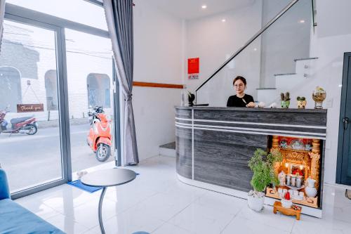 a woman standing behind a counter in a room with a scooter at Phu Quy Vibes Villa - sát biển cạnh bãi tắm in Cù Lao Thu