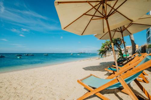 a beach with chairs and an umbrella and the ocean at Phu Quy Vibes Villa - sát biển cạnh bãi tắm in Cù Lao Thu