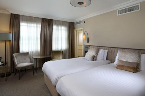 a hotel room with two beds and a chair at Castle Hotel Windsor in Windsor