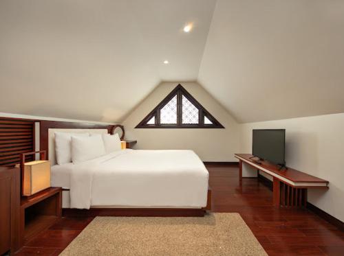 a bedroom with a white bed and a tv at Purama Villas Danang in Da Nang