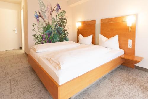 a bedroom with a large bed with a plant on the wall at Hotel Rosmarin in Bodman-Ludwigshafen
