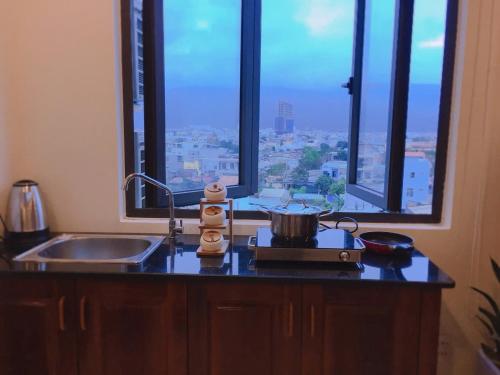 een keuken met een fornuis, een wastafel en een raam bij Son Tra Green Hotel & Apartment in Da Nang