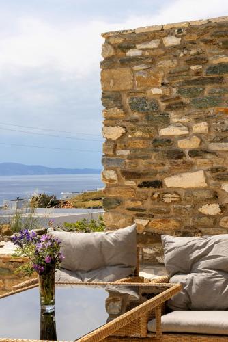 a patio with pillows and a stone wall at Epavlis Petrou Siwtou in Tinos Town