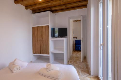 a white bedroom with a bed and a tv at Epavlis Petrou Siwtou in Tinos Town