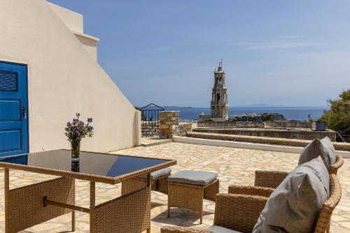 a table and chairs on a patio with a lighthouse at Epavlis Petrou Siwtou in Tinos Town