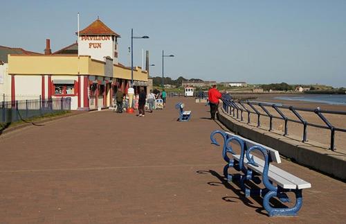 a bench on a boardwalk next to the water at Casa Sands in Spittal