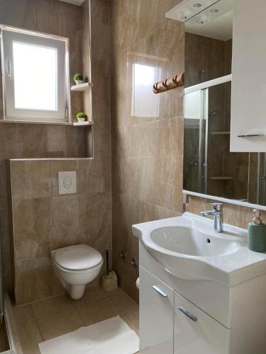Un baño con un lavabo blanco y un inodoro. en MARSHAL Apartments, en Donji Štoj