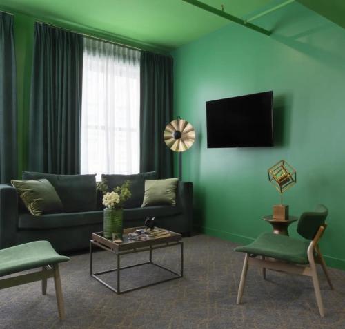 a green living room with a couch and a table at Angad Arts Hotel St Louis, Tapestry Collection by Hilton in Saint Louis