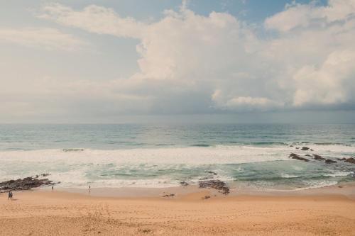 a beach with people standing in the ocean at Villa Med 14 in Ballito
