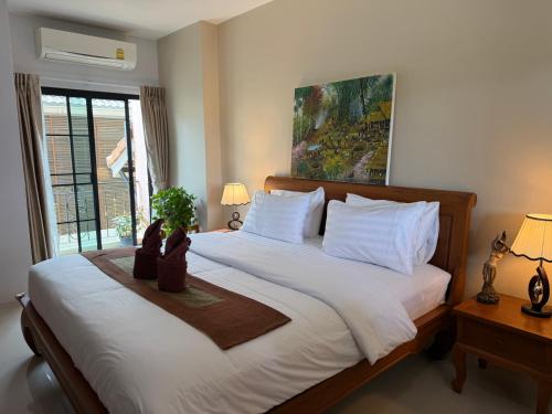 a bedroom with a large bed with a plant on it at Laph Kham House in Chiang Mai