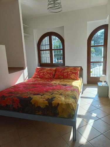 a bedroom with a bed in a room with two windows at La Casa del Merlo in Rodello