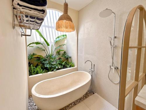 a bathroom with a tub with a plant in the window at Tujuan Jogja Villas - Kresna in Yogyakarta