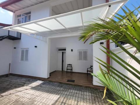 a white house with a room with a glass ceiling at Cozy Nest in Ja-Ela