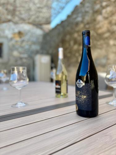 une bouteille de vin posée sur une table avec deux verres dans l'établissement L'Oustal de Papet, à Ferrals-lès-Corbières