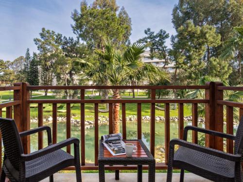 a table on a porch with two chairs and a table with a book at Rixos Premium Tekirova - The Land of Legends Access in Tekirova