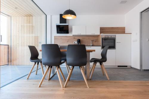 a kitchen with black chairs and a wooden table at MESNERHOF CHALET - Ruhe, Rückzug & Südtiroler Charme mit kostenlosem Parken in der Tiefgarage in Bressanone
