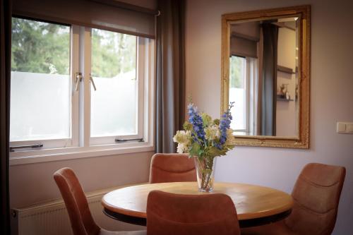 Fenced Backyard with Covered Porch and Free Bikes في Doornspijk: إناء من الزهور على طاولة مع مرآة