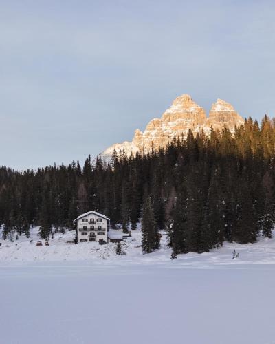 a house in the snow in front of a mountain at Hotel Miralago in Misurina