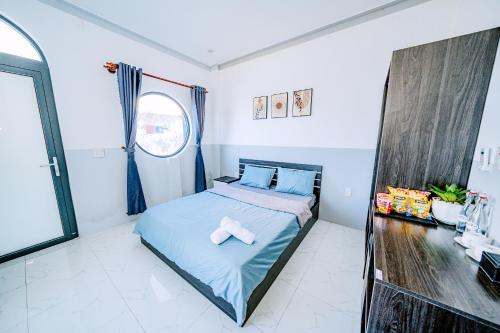 a bedroom with a bed with blue sheets and a window at Phu Quy Vibes Villa - sát biển cạnh bãi tắm in Cù Lao Thu