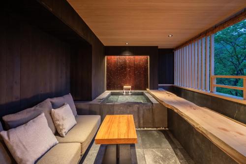 a hot tub in a room with a couch and a table at Nazuna Hakone Miyanosita in Miyanoshita
