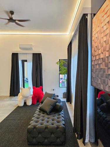a living room with a black leather couch and stuffed animals at Designer house with cabin rooms in Gelang Patah