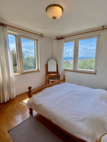 a bedroom with a large bed and two windows at Lilys Paradise in Orebić