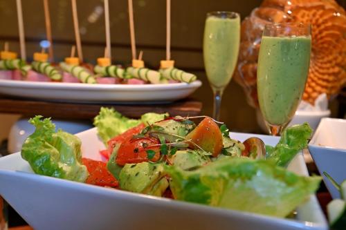 a salad in a bowl on a table with two champagne glasses at Holiday Inn - Bulawayo by IHG in Bulawayo