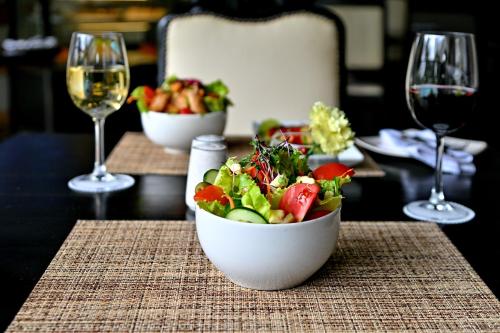 a bowl of salad on a table with glasses of wine at Holiday Inn - Bulawayo by IHG in Bulawayo