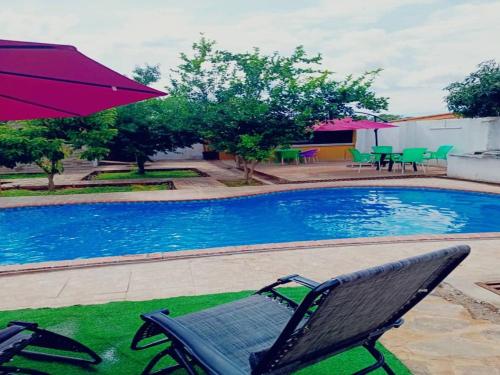a chair and an umbrella next to a swimming pool at Glamour Lodges and Apartments in Livingstone