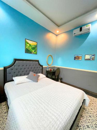 a bedroom with a white bed with a blue wall at Sunset Homestay Villa Tam Đảo in Tam Ðảo