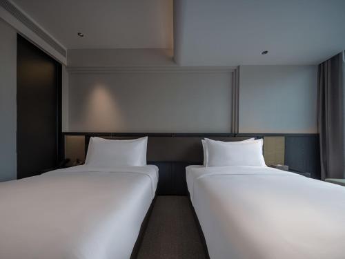 two beds sitting next to each other in a room at 中濠悦际酒店 深圳国际会展中心店 in Shenzhen