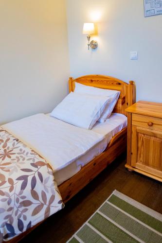 a bedroom with a bed with a wooden headboard and a table at Sasréti Vadászkastély Almamellék in Almamellék