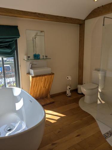 a bathroom with a white tub and a toilet at The Barge Inn, Honeystreet in Alton Barnes
