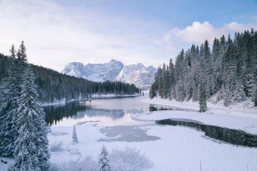 a river covered in snow with trees and mountains at Hotel Miralago in Misurina