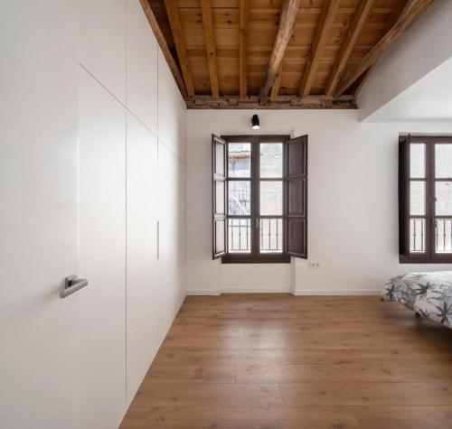 a bedroom with white walls and a wooden ceiling at DreamStay - Oficios Apartamento in Granada